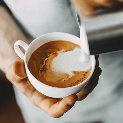 Barista making tasty appetizing coffee cappuccino latte pouring milk. Coffee preparation concept. Closeup. Horizontal.